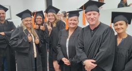 A group of graduates smiling at camera in graduation gowns
